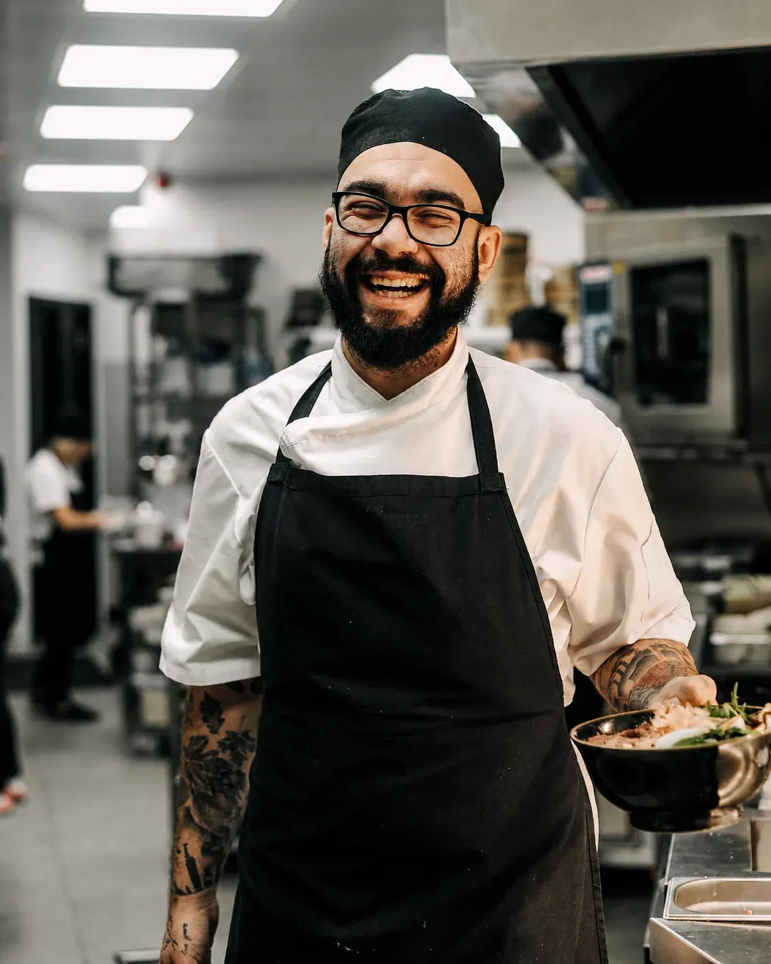 Smiling chef in a commercial kitchen wearing a freshly laundered apron